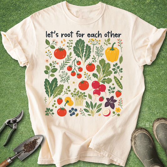Ivory Comfort Colors t-shirt featuring colorful vegetables, herbs, flowers, and garden plants with the phrase "Let's Root for Each Other" above the artwork.