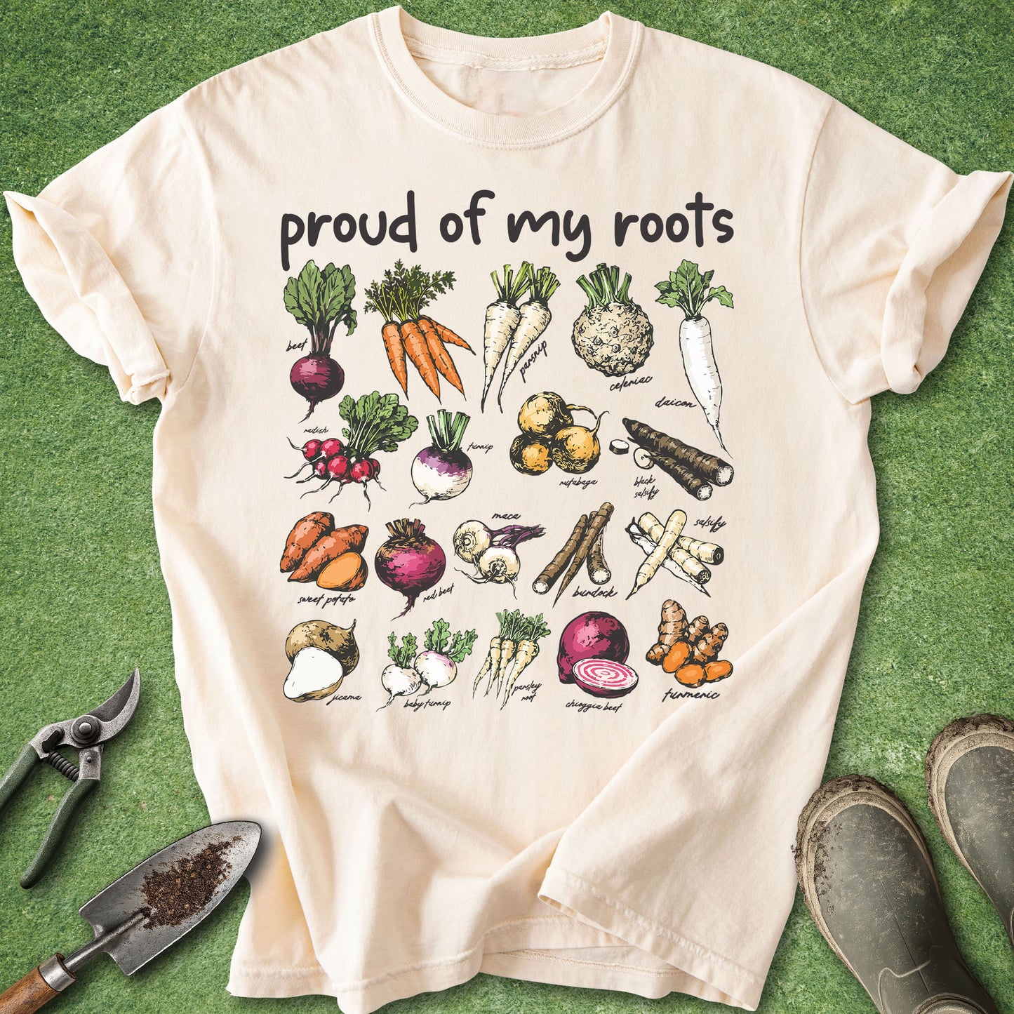 Ivory Comfort Colors t-shirt featuring the phrase "Proud of My Roots" above illustrated root vegetables including carrots, beets, radishes, parsnips, daikon, sweet potatoes, rutabagas, turmeric, and other garden crops.