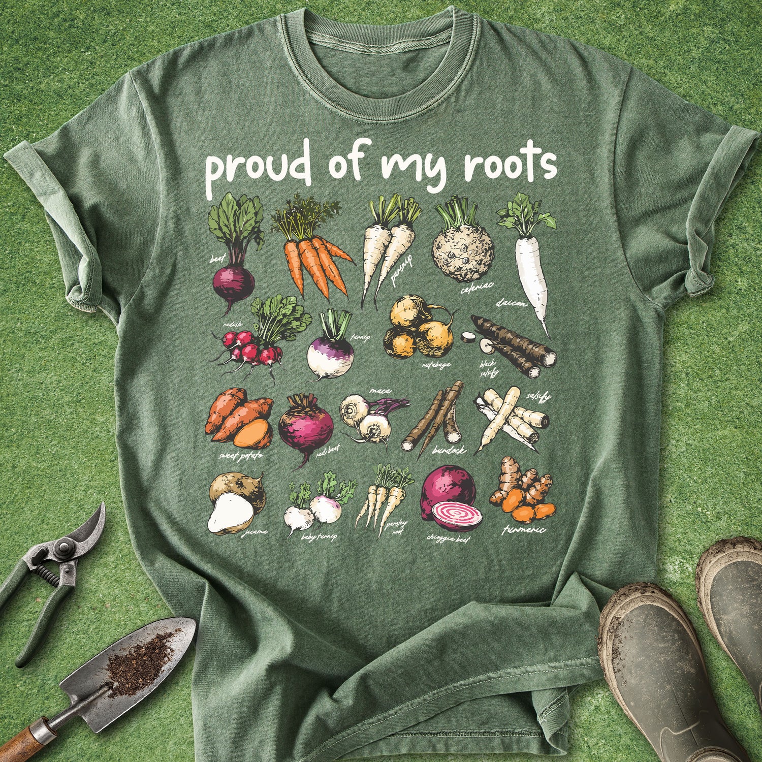 Green t-shirt with vegetable illustrations and 'proud of my roots' text on a grass background.