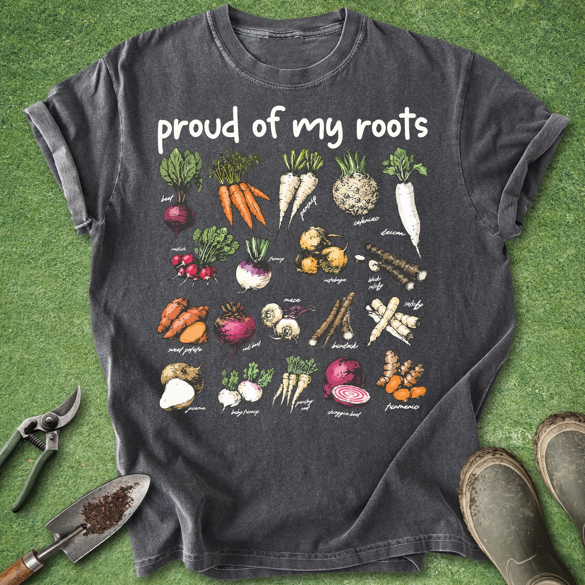 Dark gray t-shirt with vegetable illustrations and 'proud of my roots' text on a green grass background.