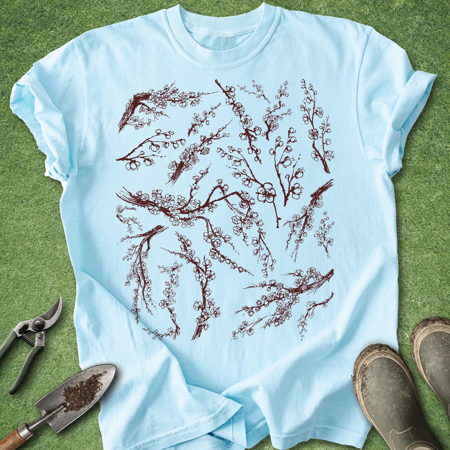 Light blue t-shirt with red floral design on a green grass background