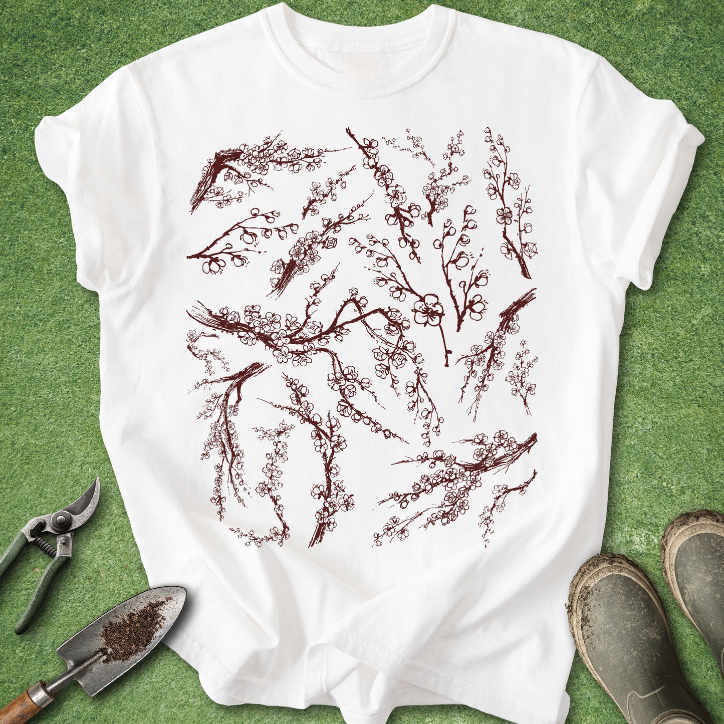 White t-shirt with red floral design on a green grass background