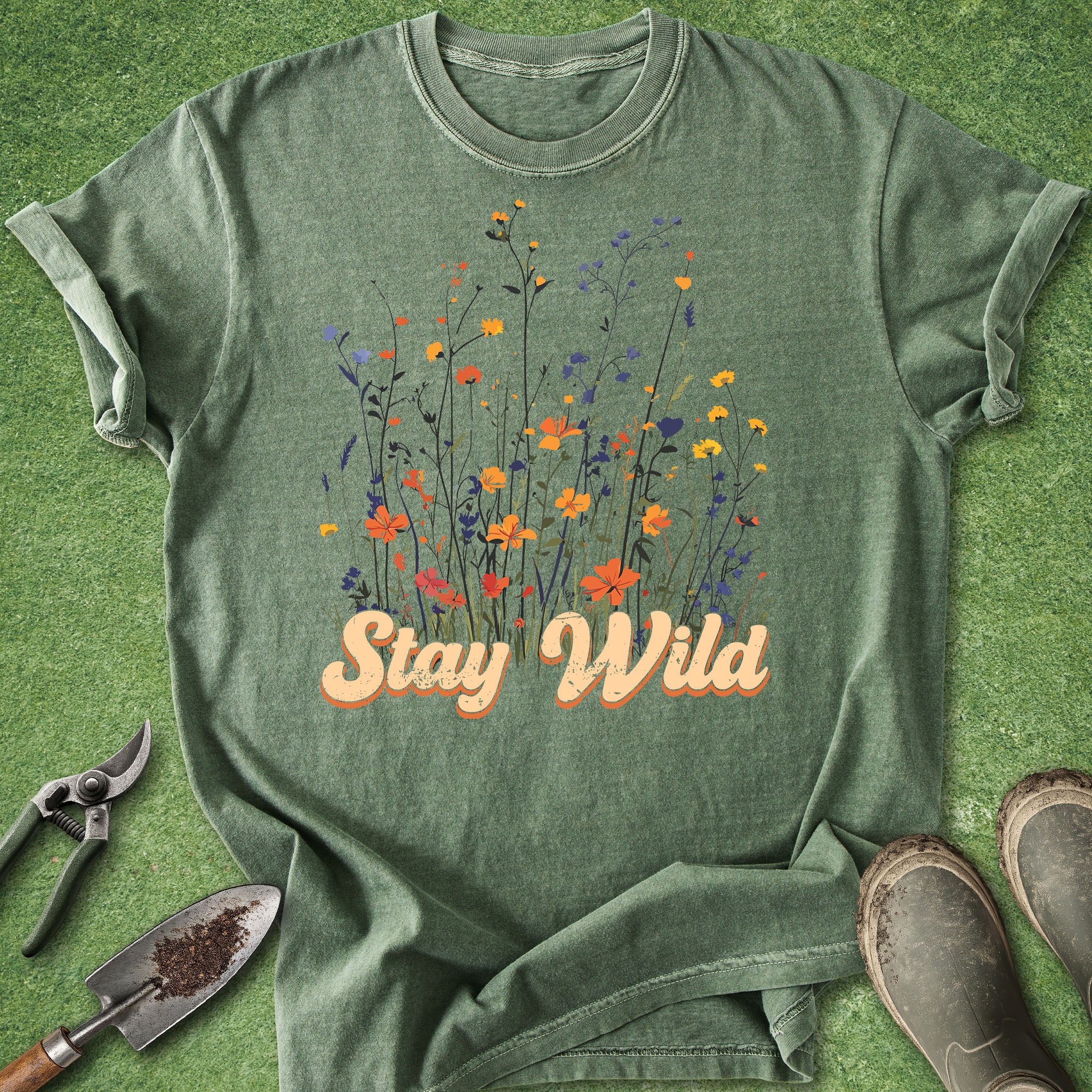 Green t-shirt with 'Stay Wild' text and floral design on a grass background