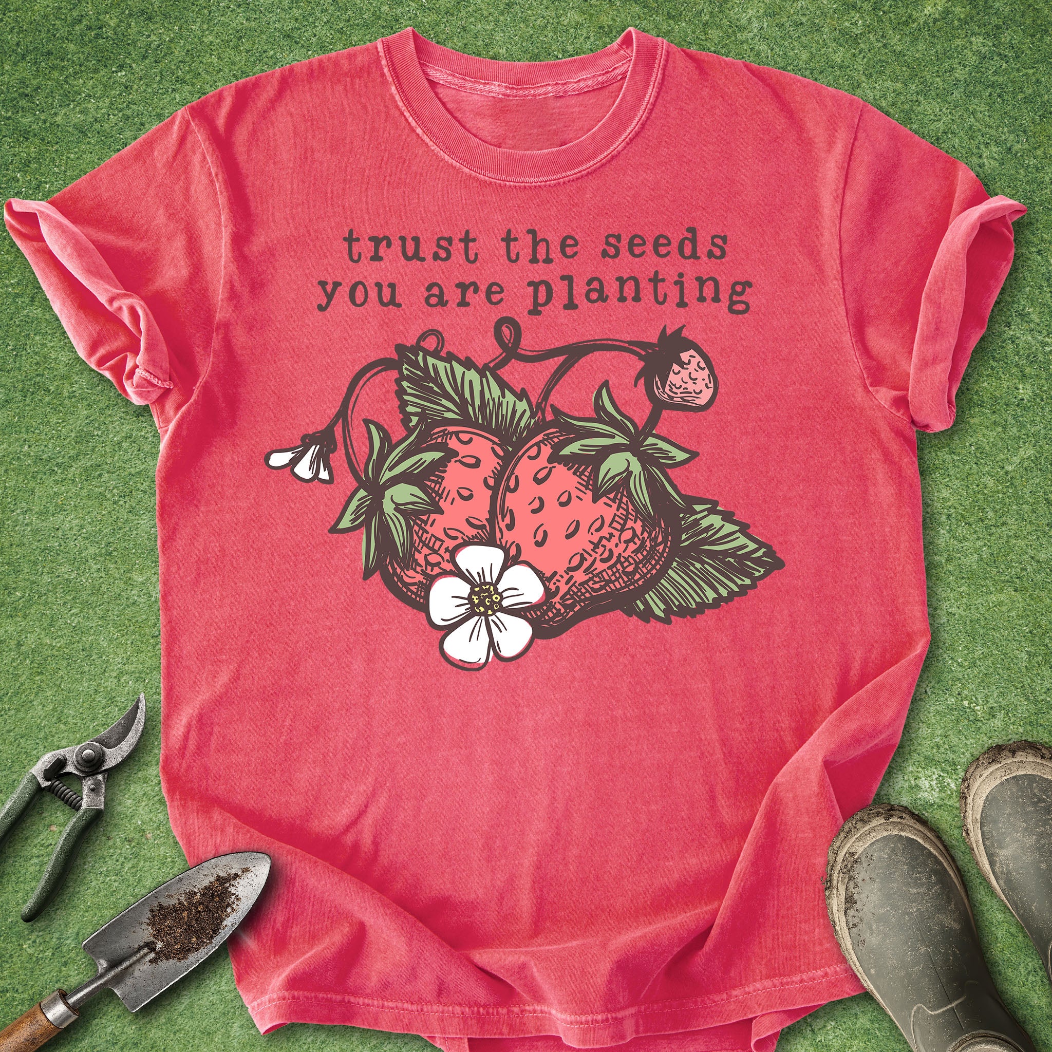 Red t-shirt with strawberry graphic and text on a green grass background