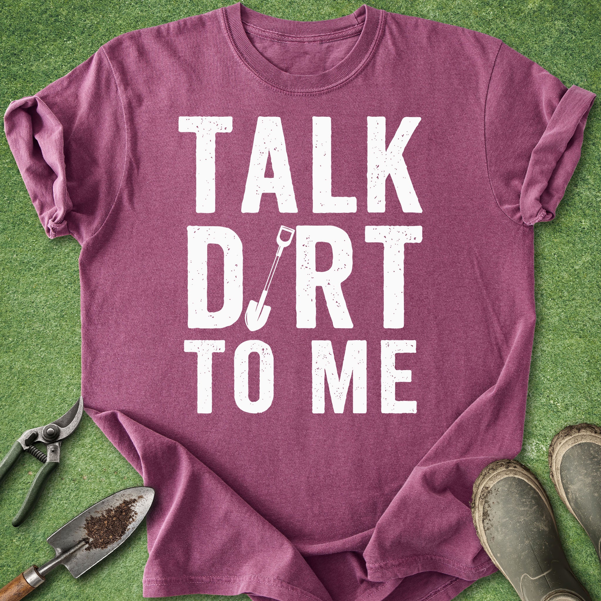 Purple t-shirt with 'Talk Dirt to Me' text on a green background with gardening tools.
