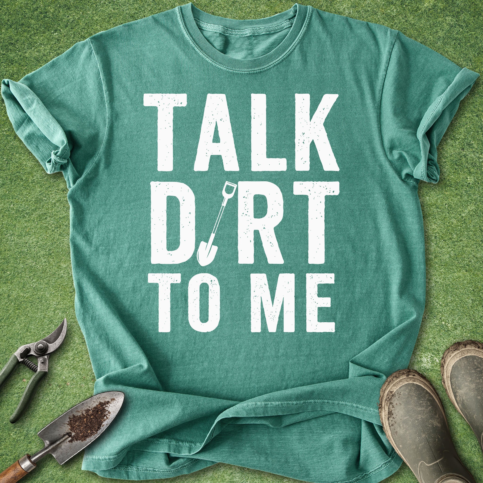 Green t-shirt with 'Talk Dirt to Me' text on a grass background