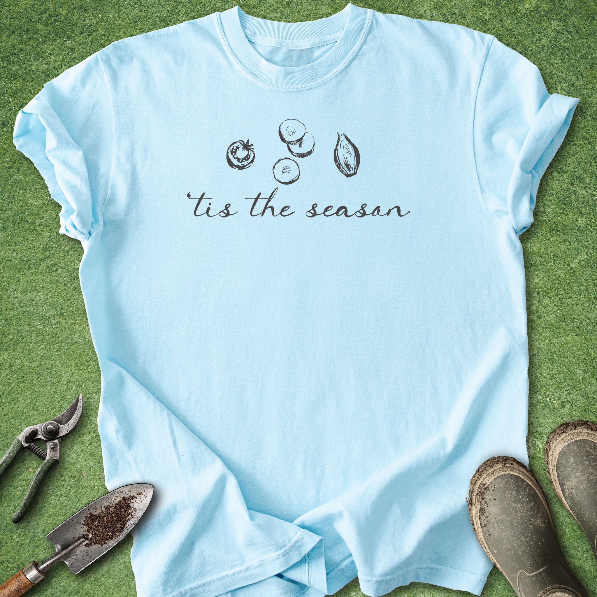 Light blue t-shirt with 'tis the season' text and gardening tools on a grass background