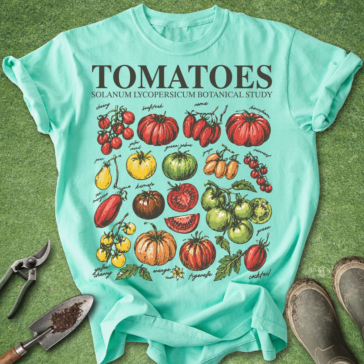 Mint green t-shirt with tomato graphic and text on a grass background