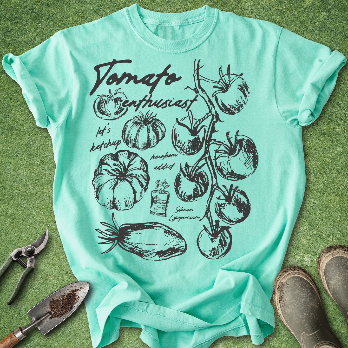 Mint green t-shirt with tomato graphic design on a grass background