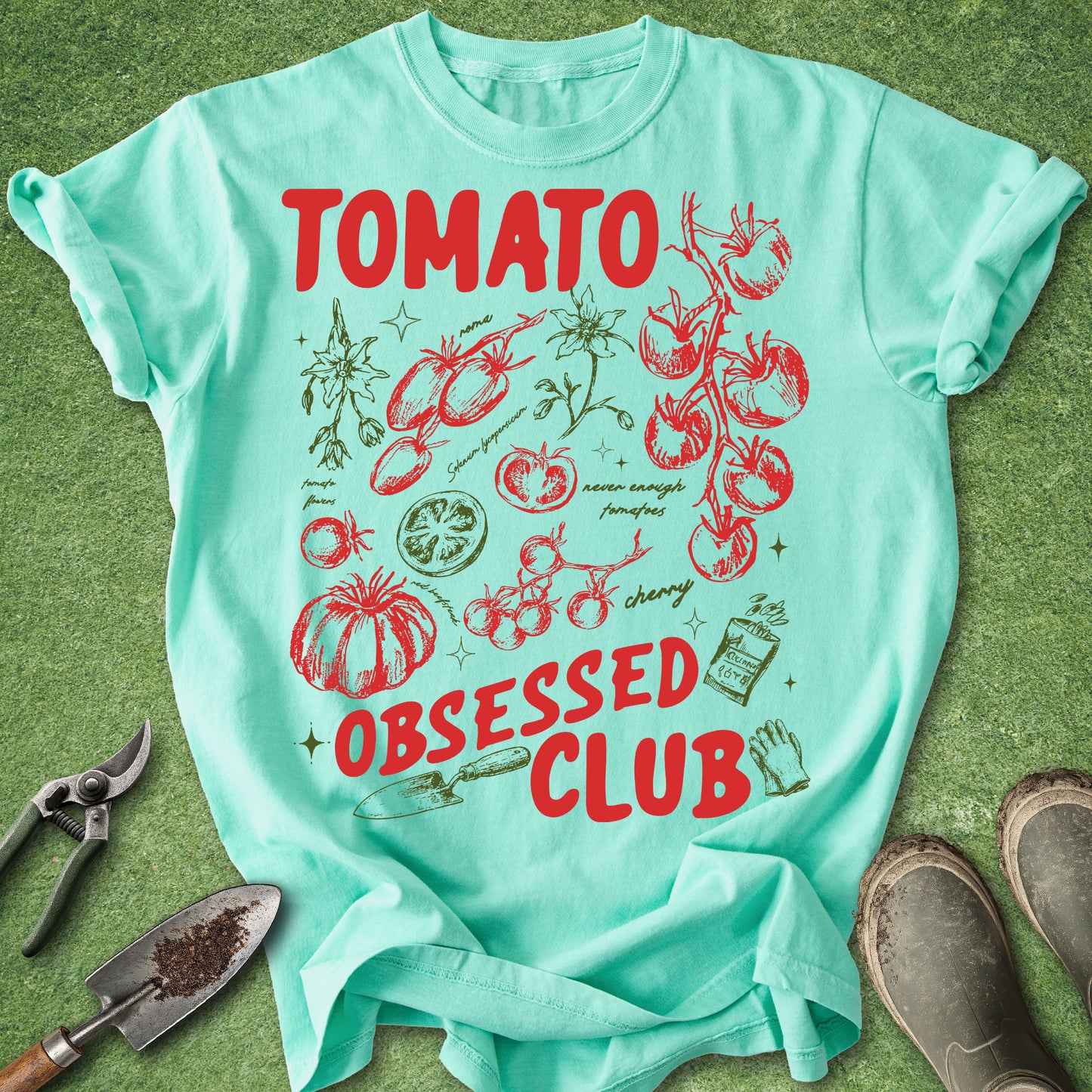 Mint green t-shirt with tomato-themed design on a grass background