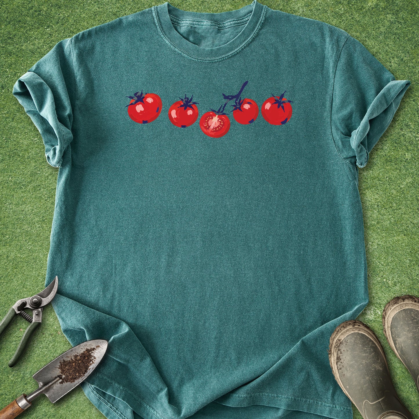 Teal t-shirt with tomato design on a grass background