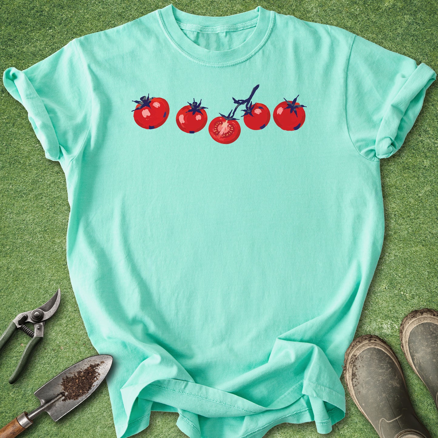 Mint green t-shirt with tomato graphic on a grass background