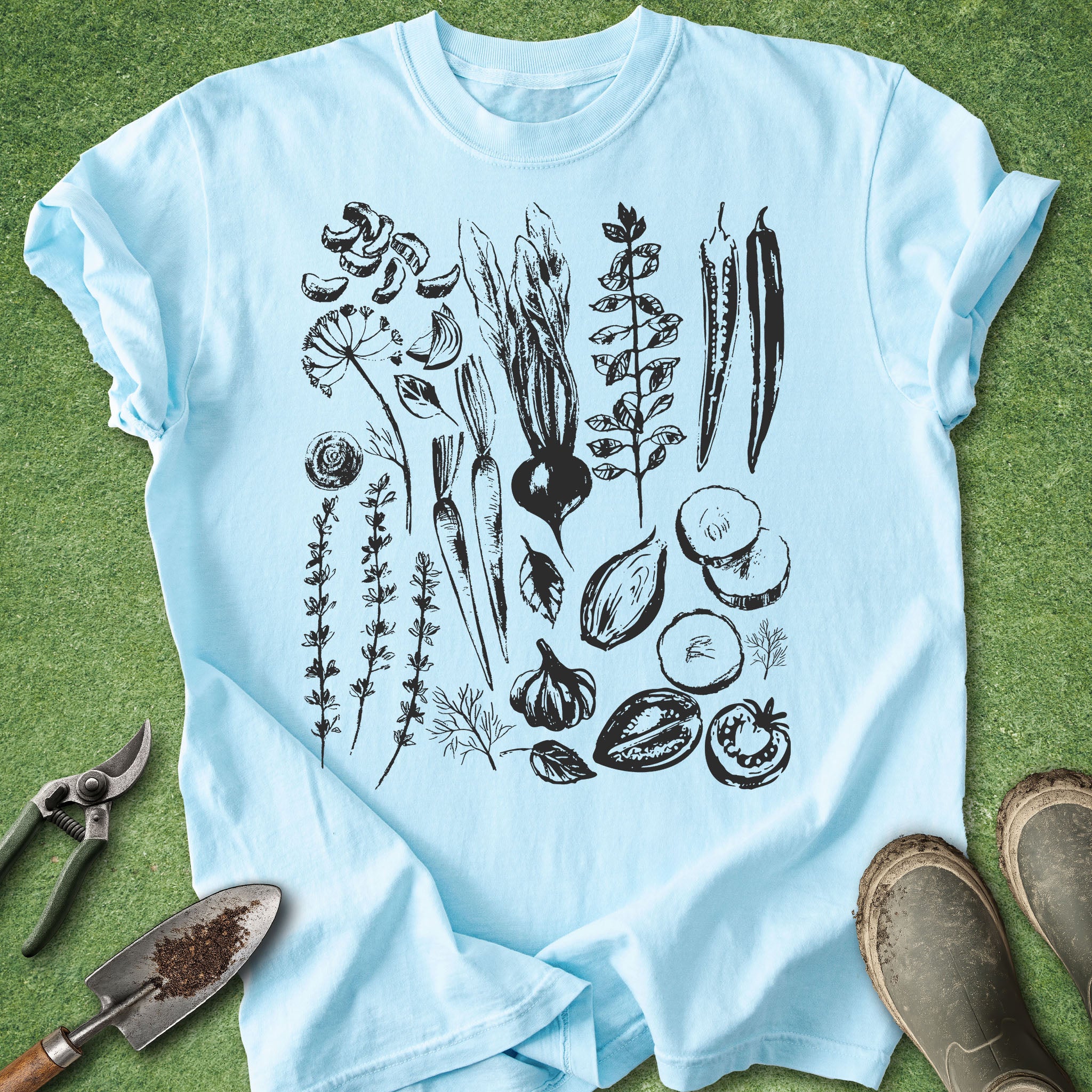 Light blue t-shirt with black botanical illustrations on a green grass background