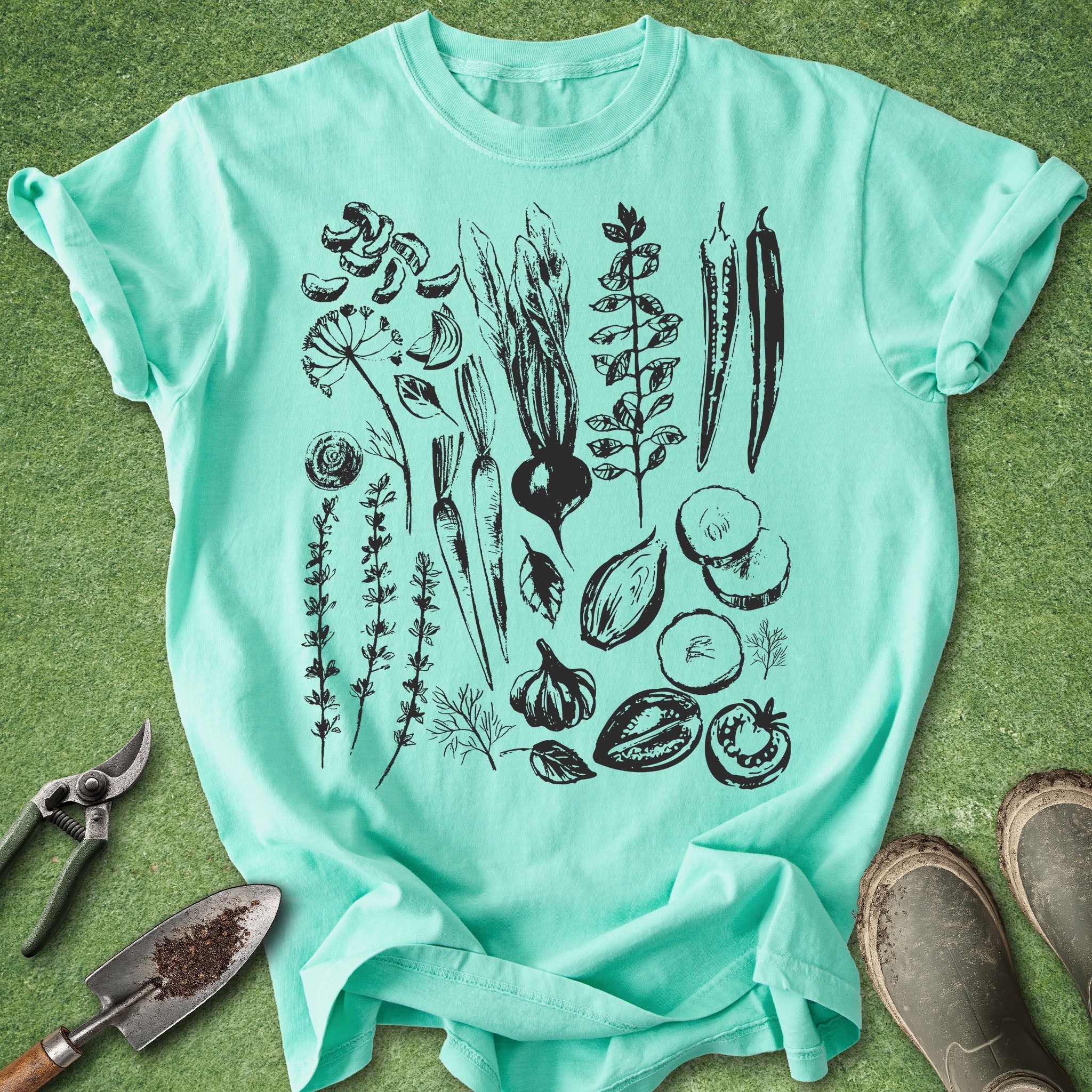 Mint green t-shirt with black botanical illustrations on a grass background
