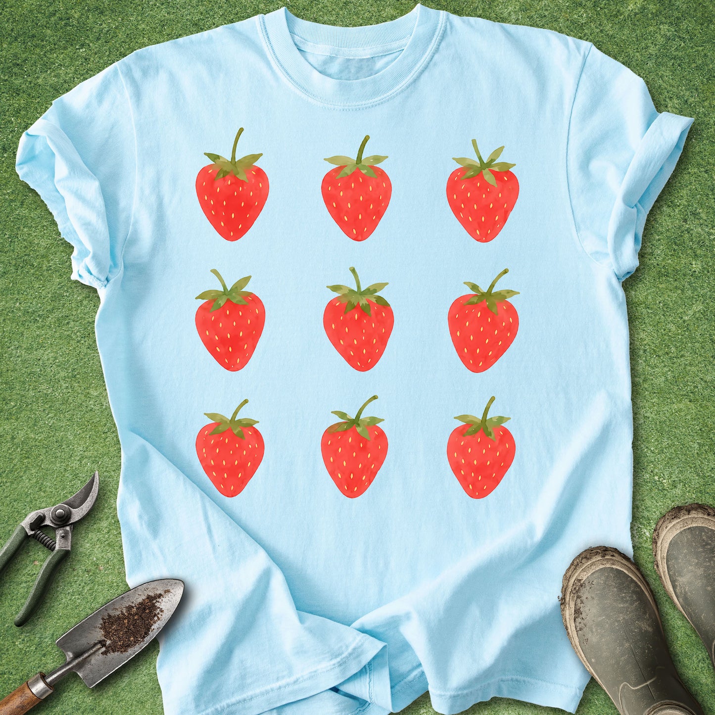 Light Blue t-shirt featuring nine hand-painted watercolor strawberries arranged in a simple three-by-three grid with bright red berries and green leaves.