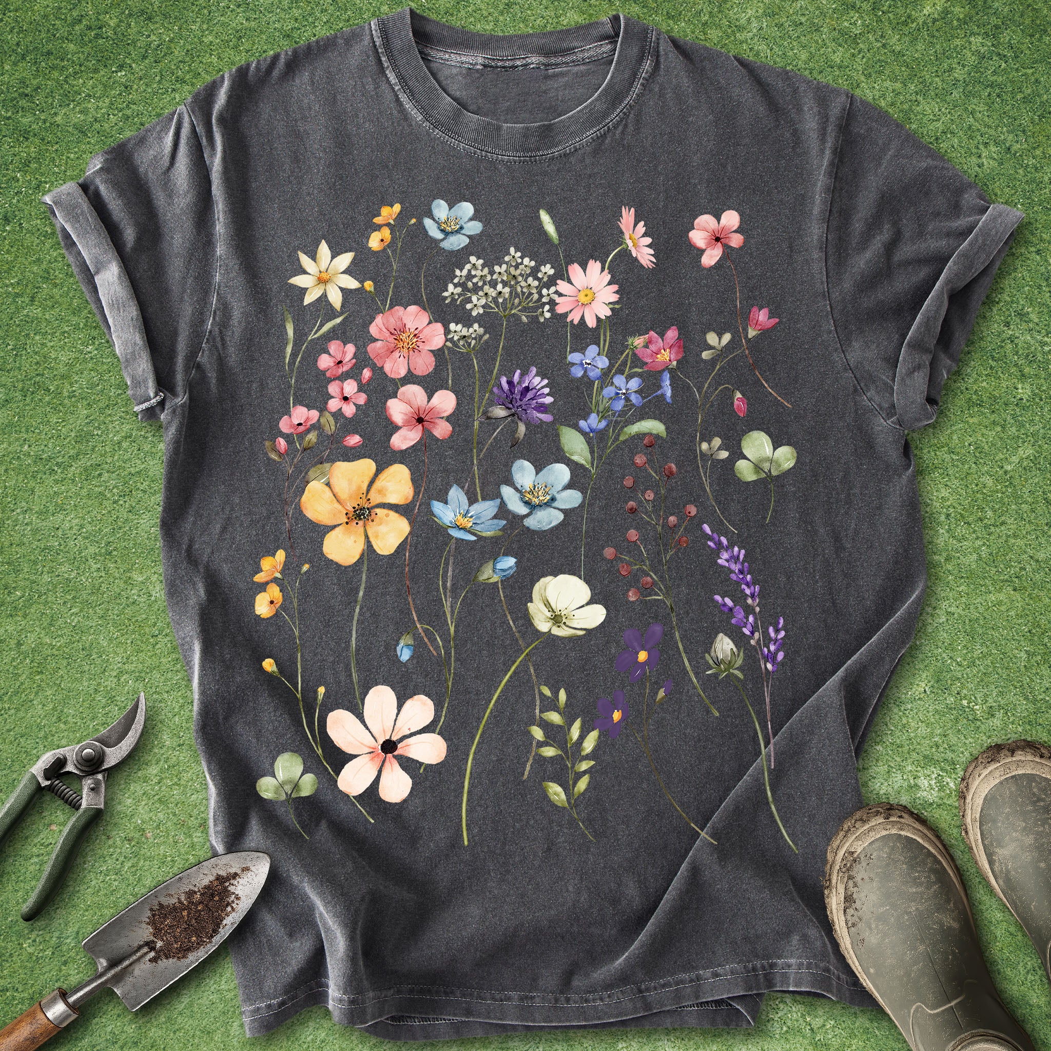 Black t-shirt with colorful floral design on a green grass background