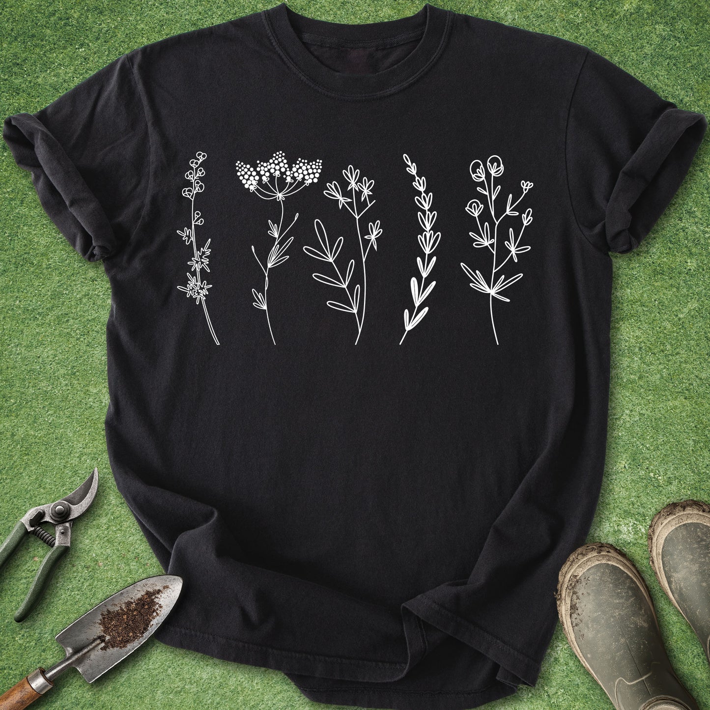 Black t-shirt with white floral designs on a green grass background