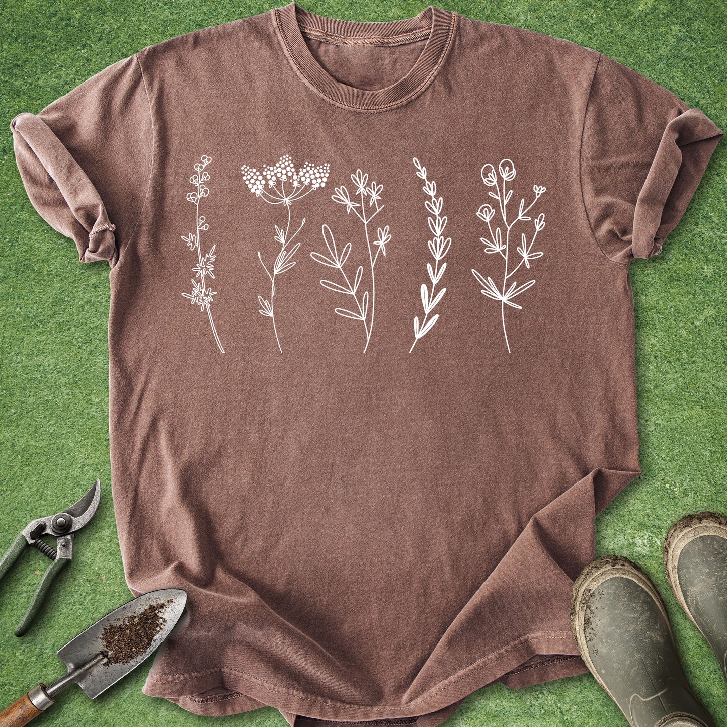 Brown t-shirt with white floral designs on a green grass background