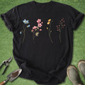 Black t-shirt with floral designs on a green grass background