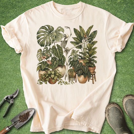 Ivory t-shirt featuring a dancing skeleton surrounded by lush tropical houseplants including Monstera, Philodendron, Pothos and Bird of Paradise.