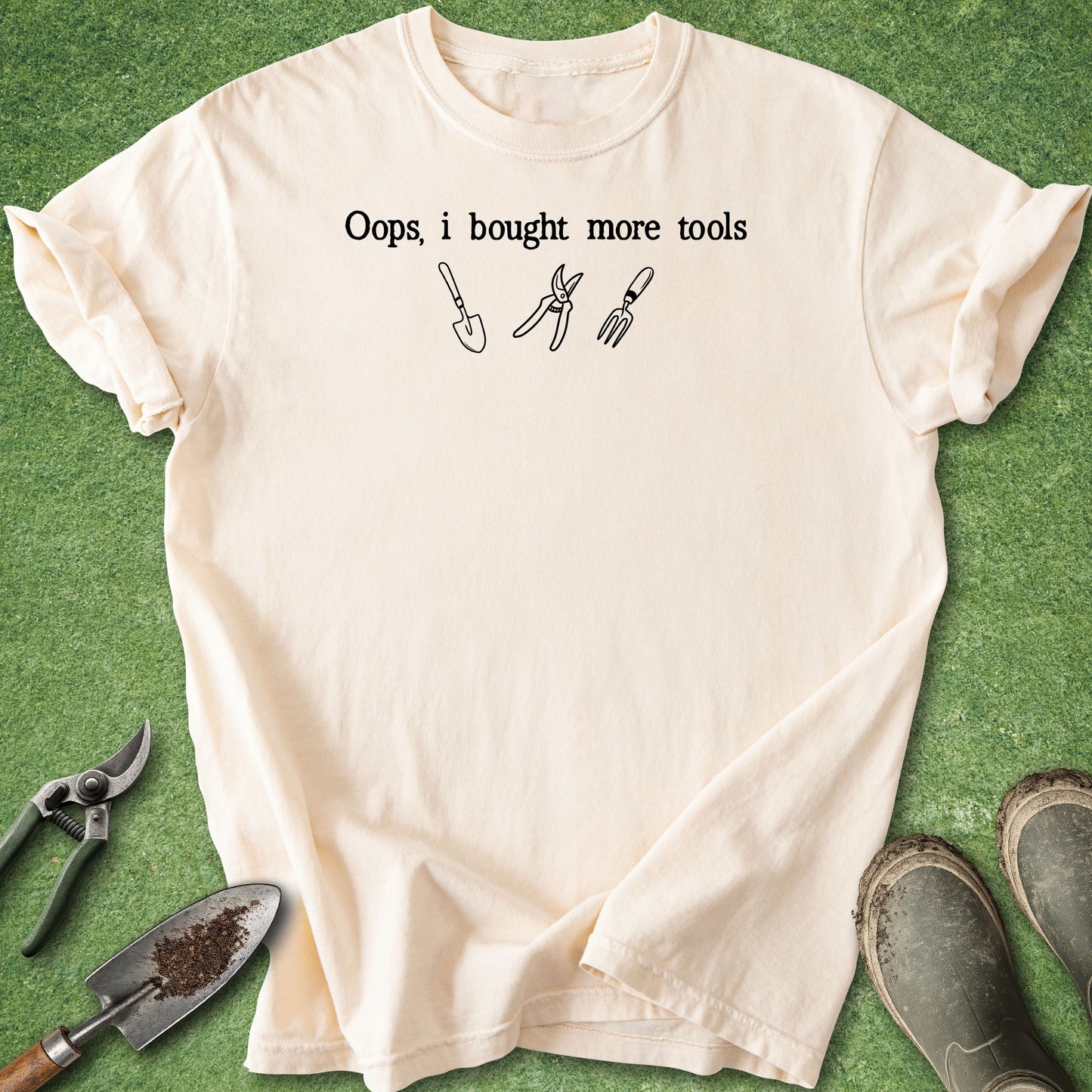 Beige t-shirt with text and tool icons on a green grass background