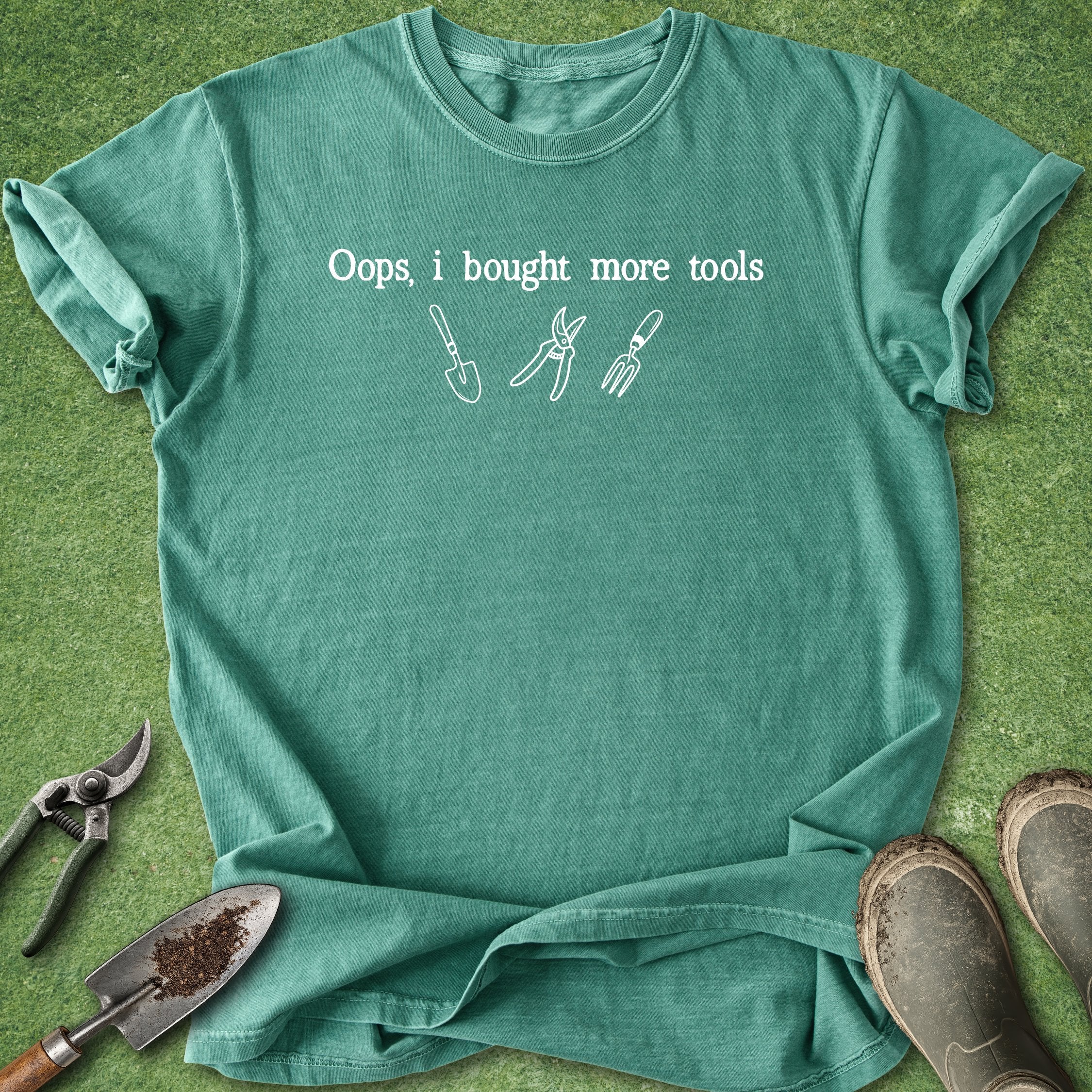 Green t-shirt with 'Oops, I bought more tools' text and gardening tool illustrations on a green background.