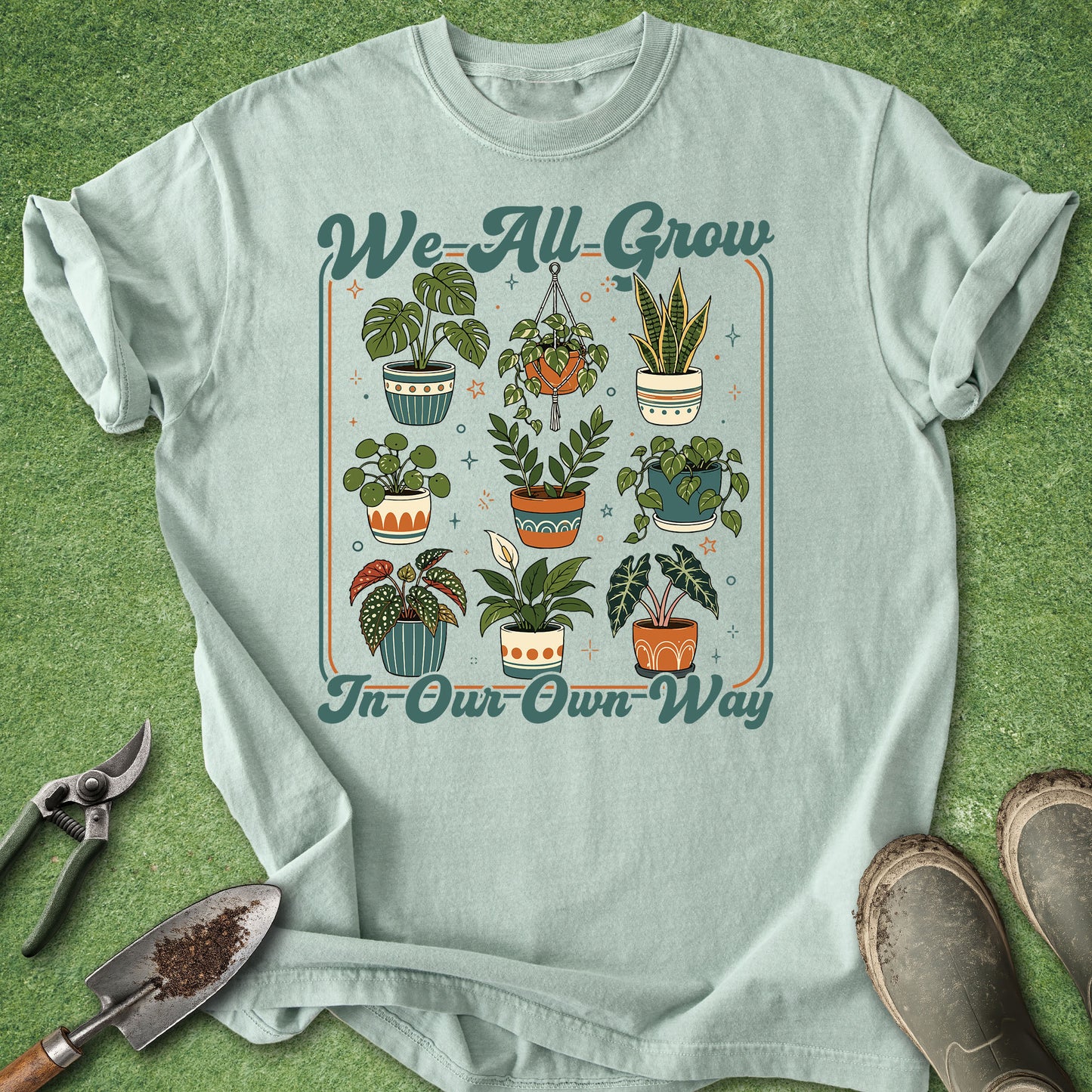 Bay color gardening t-shirt with We All Grow in Our Own Way text and colorful retro potted houseplant illustrations.