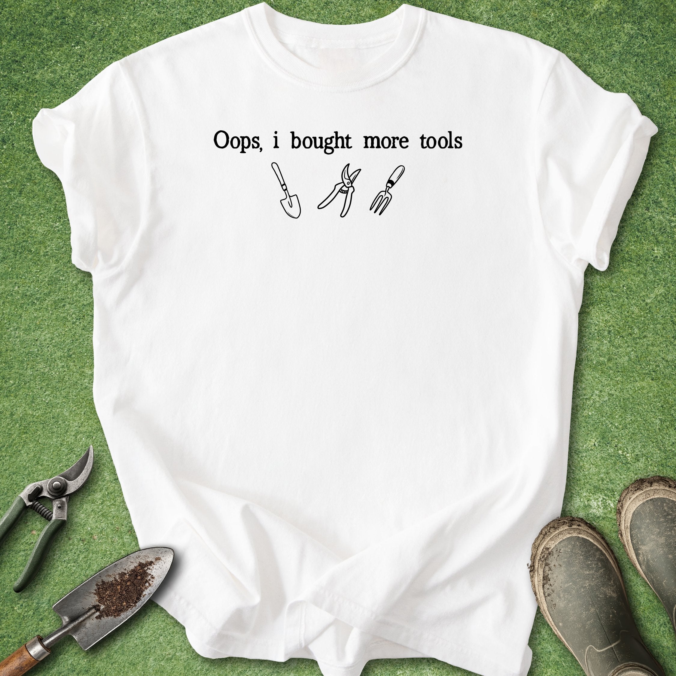White t-shirt with 'Oops, I bought more tools' text and tool icons on a green background with gardening tools.