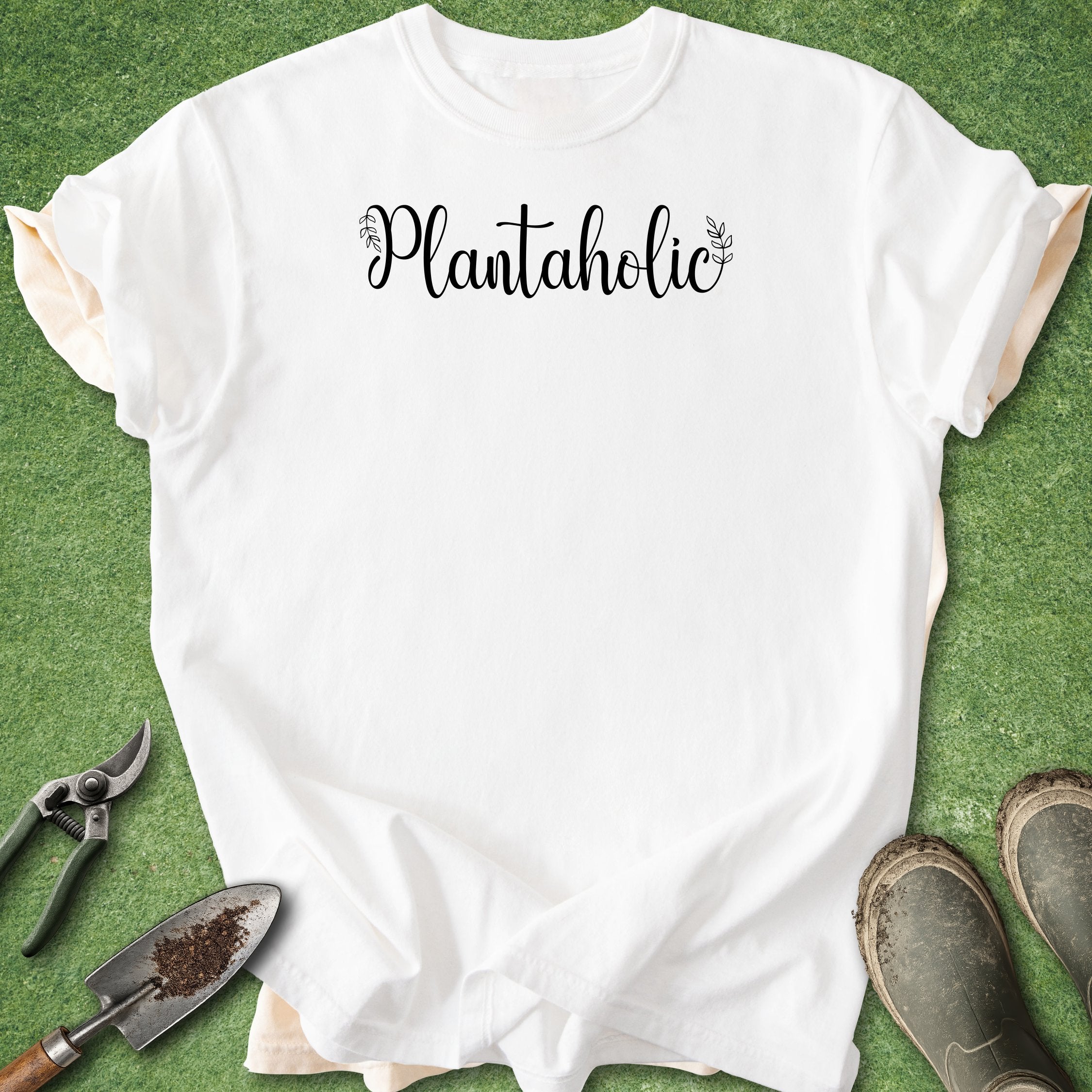 White t-shirt with 'Plantaholic' text on a green grass background
