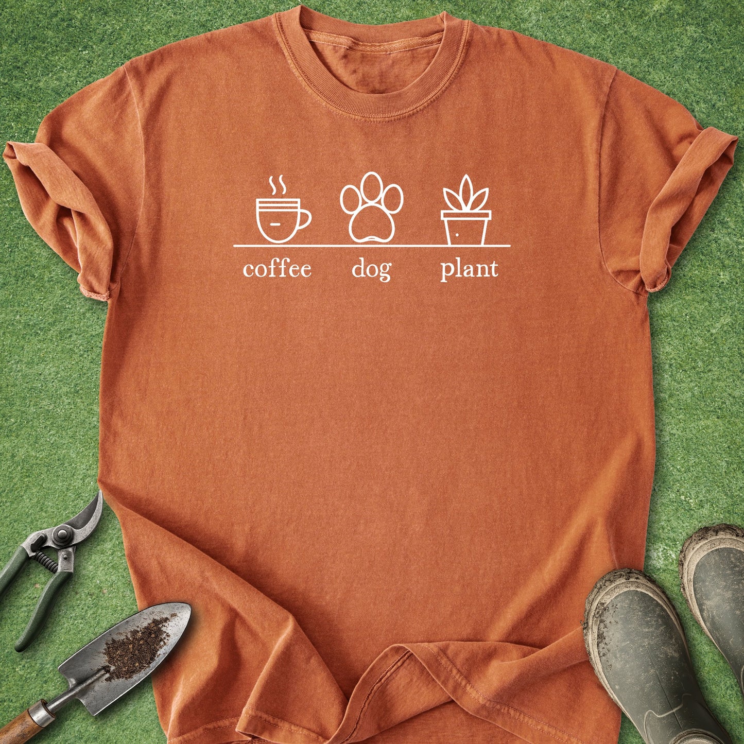 Orange t-shirt with 'coffee, dog, plant' graphic on a grass background