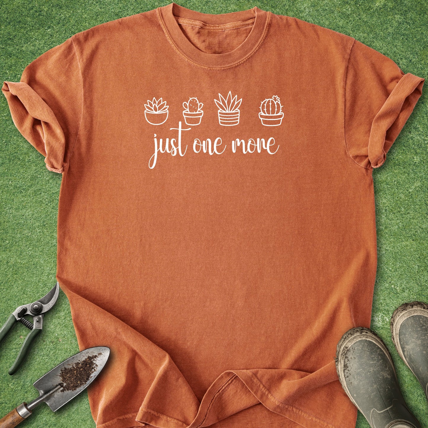 Orange t-shirt with plant designs and text on a green grass background