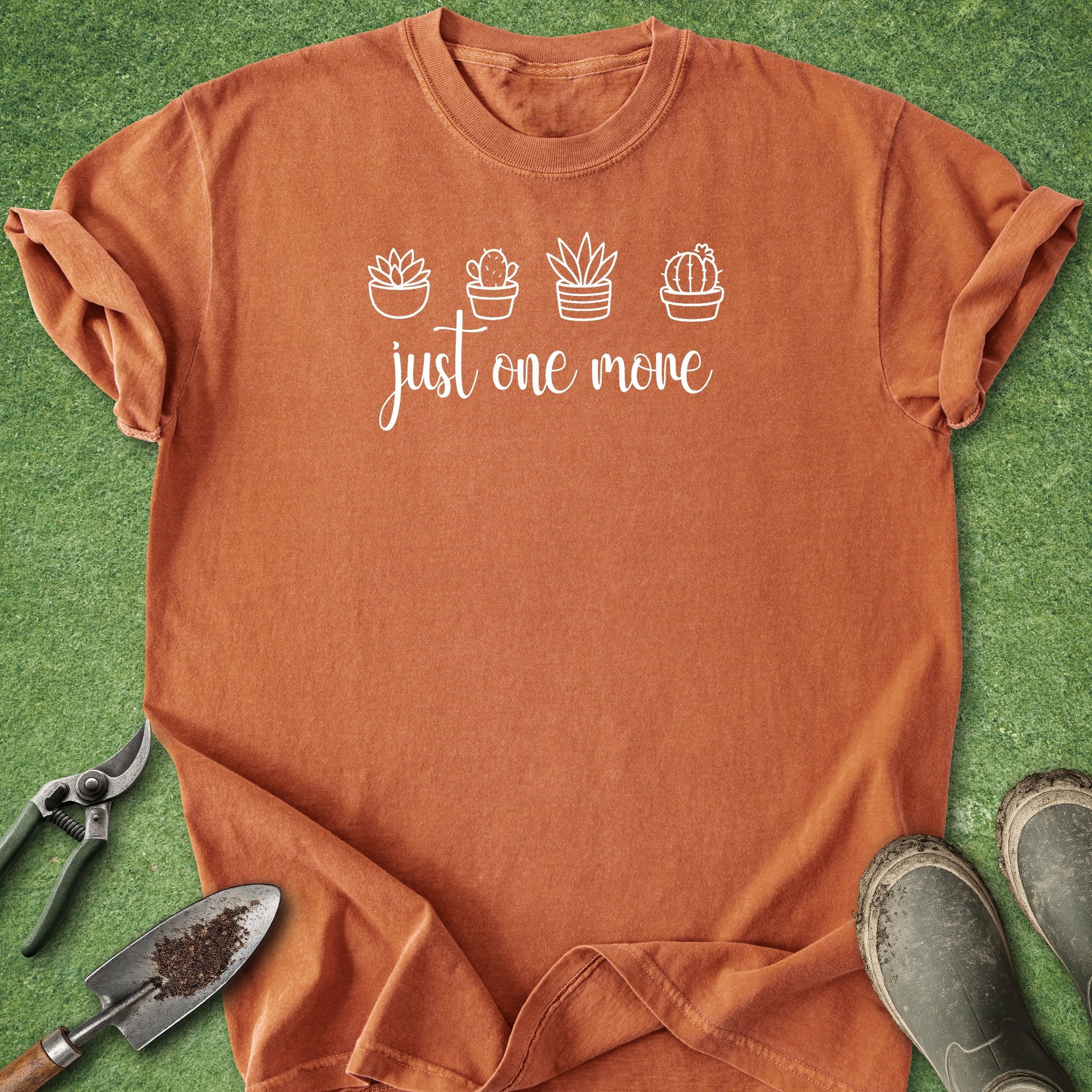 Orange t-shirt with plant designs and text on a green grass background