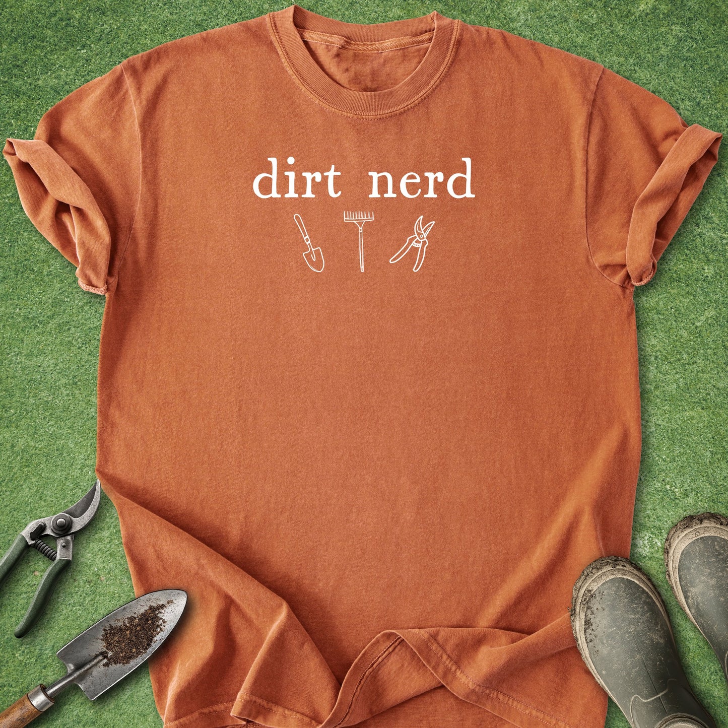 Orange t-shirt with 'dirt nerd' text and gardening tools on a grass background